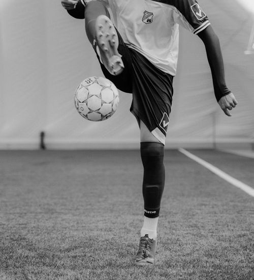 Man performing a strength and balance exercise in a dark room.